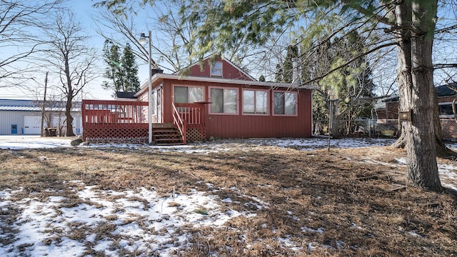 snow covered back of property with a deck