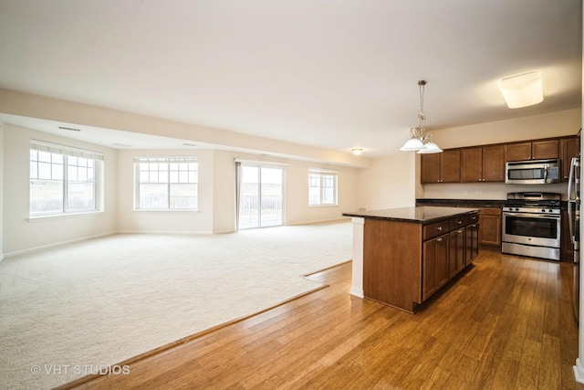 kitchen with stainless steel appliances, a center island, carpet floors, a wealth of natural light, and decorative light fixtures