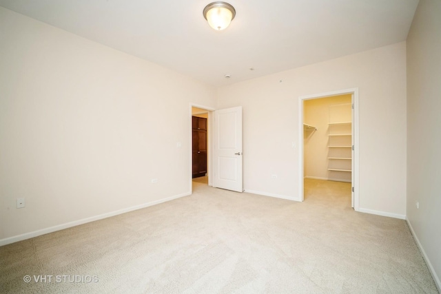 unfurnished bedroom with a walk in closet, light colored carpet, and a closet