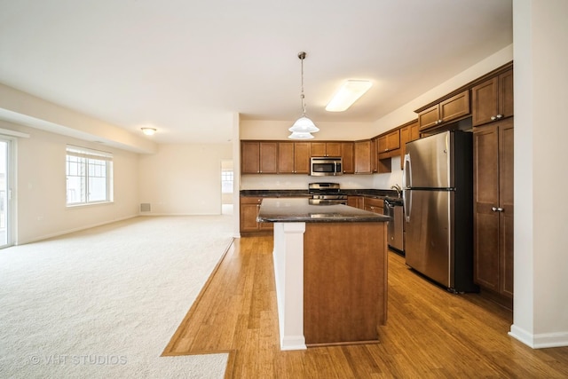 kitchen featuring pendant lighting, light wood-type flooring, stainless steel appliances, and a kitchen island