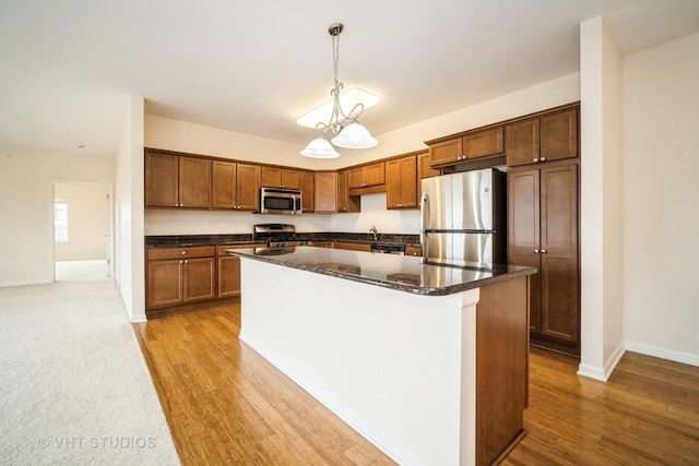 kitchen with stainless steel appliances, hanging light fixtures, light hardwood / wood-style floors, and a kitchen island