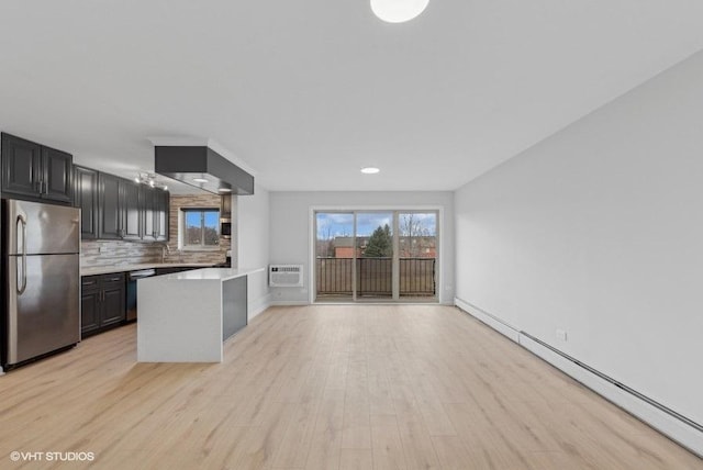 kitchen featuring a wall mounted air conditioner, light hardwood / wood-style flooring, backsplash, appliances with stainless steel finishes, and a baseboard heating unit