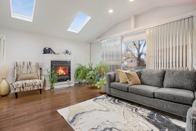 living room with vaulted ceiling with skylight, a fireplace, and hardwood / wood-style floors