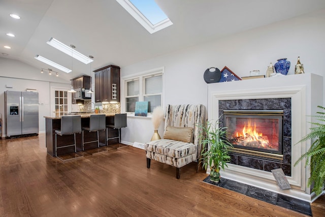 sitting room with dark hardwood / wood-style flooring, sink, a high end fireplace, and vaulted ceiling with skylight