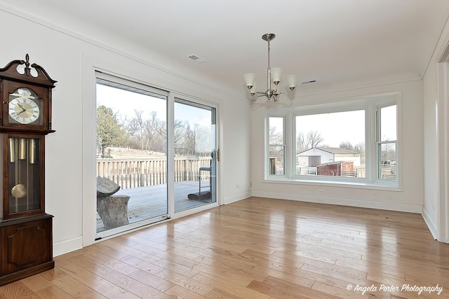 unfurnished dining area featuring an inviting chandelier, plenty of natural light, and light wood-type flooring