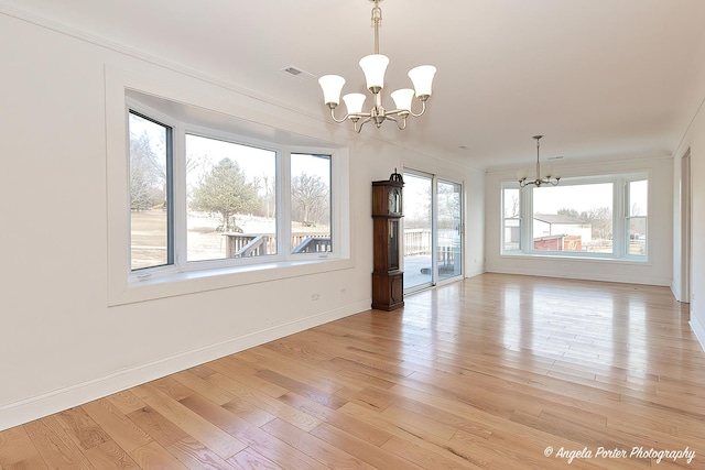 spare room with a notable chandelier, light hardwood / wood-style flooring, and ornamental molding