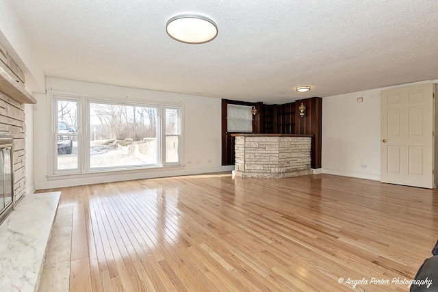 unfurnished living room with light hardwood / wood-style flooring, a fireplace, and a textured ceiling