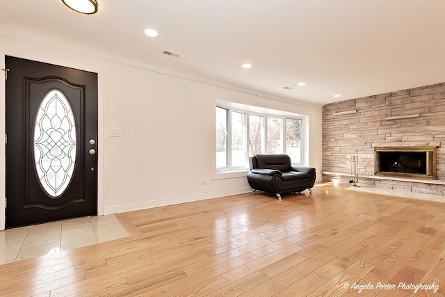 entrance foyer featuring a stone fireplace and light hardwood / wood-style flooring