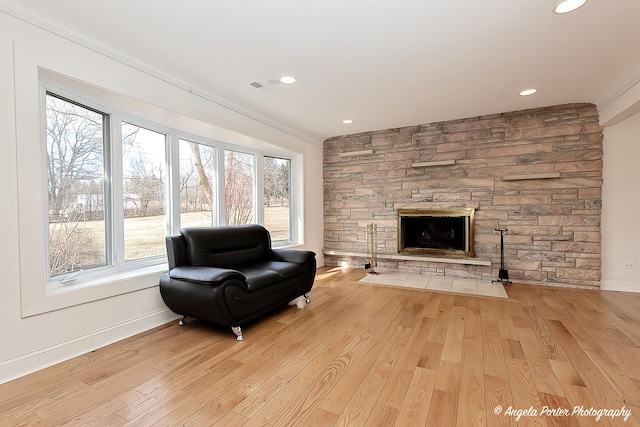 sitting room featuring a stone fireplace and light hardwood / wood-style flooring