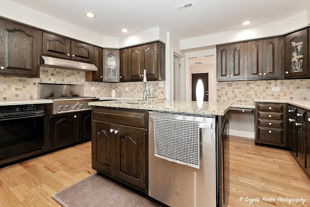 kitchen with dishwashing machine, dark brown cabinetry, oven, and light wood-type flooring