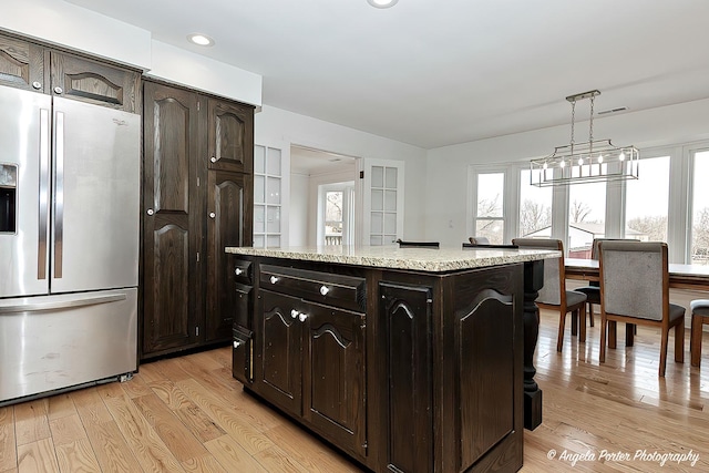 kitchen with pendant lighting, dark brown cabinets, stainless steel fridge, and a center island