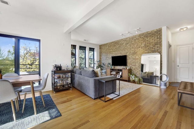 living room with track lighting, beam ceiling, and light wood-type flooring