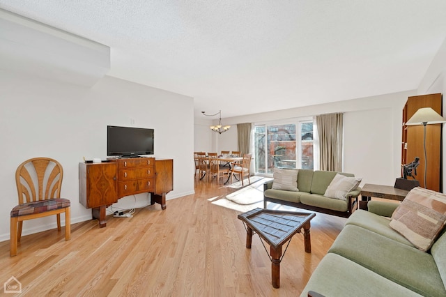 living room featuring light hardwood / wood-style floors, a textured ceiling, and a notable chandelier