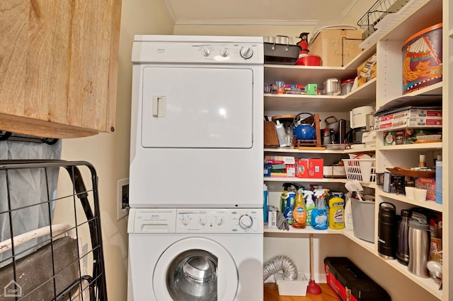 laundry area featuring stacked washer and dryer and ornamental molding