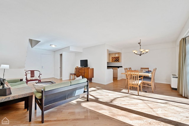 living room with radiator heating unit, light hardwood / wood-style floors, and a chandelier