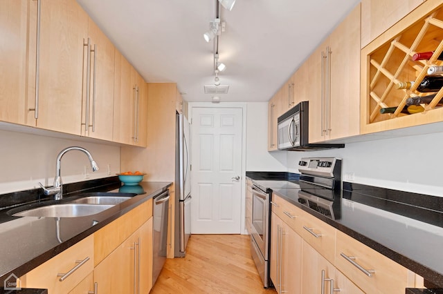 kitchen featuring appliances with stainless steel finishes, sink, light brown cabinets, and light wood-type flooring