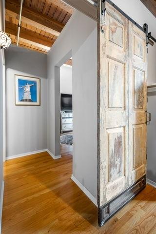 corridor featuring hardwood / wood-style flooring, beamed ceiling, a barn door, and wooden ceiling