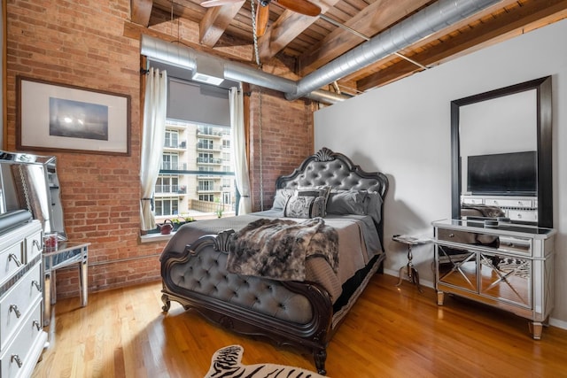 bedroom featuring brick wall and light hardwood / wood-style flooring