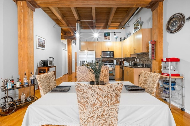 dining space featuring sink, a towering ceiling, and light hardwood / wood-style floors