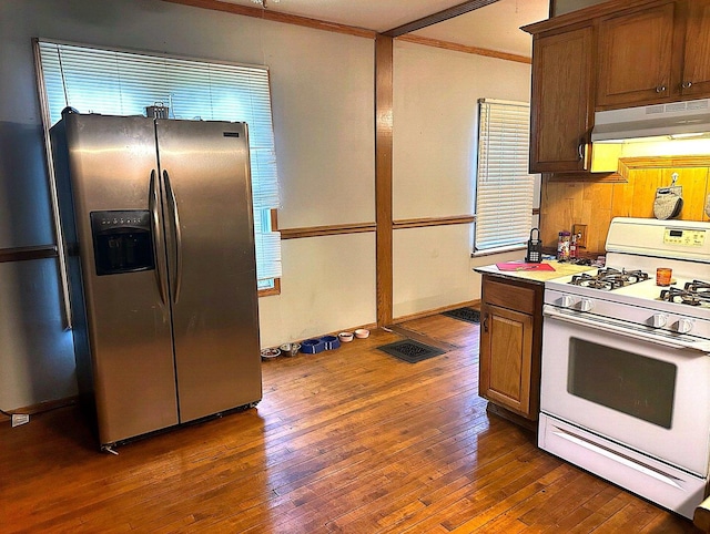 kitchen with ornamental molding, dark hardwood / wood-style floors, white range with gas stovetop, and stainless steel fridge with ice dispenser