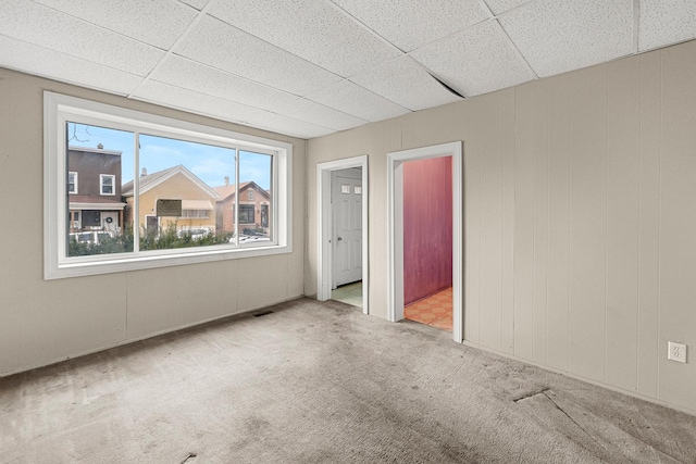 carpeted empty room featuring a paneled ceiling