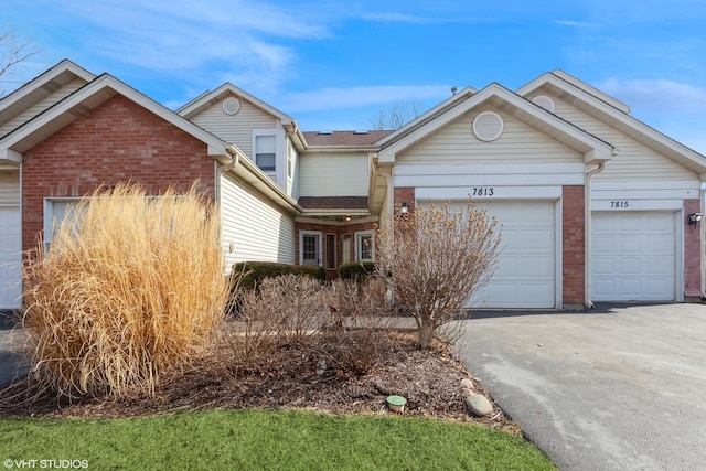 ranch-style house featuring aphalt driveway, an attached garage, and brick siding