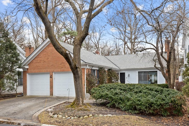 ranch-style house with a garage, a chimney, and brick siding