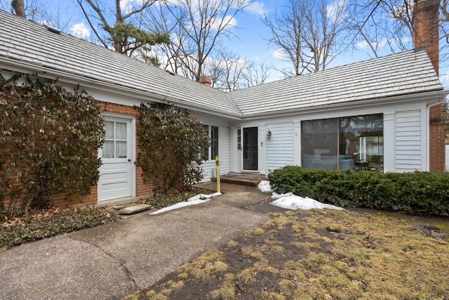 property entrance with brick siding and a chimney