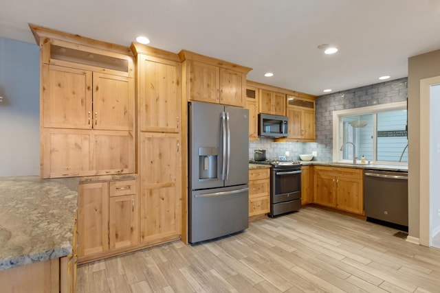 kitchen featuring stainless steel appliances, light brown cabinetry, light wood-style floors, backsplash, and recessed lighting