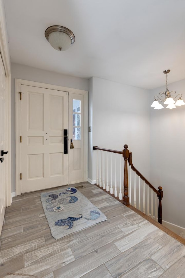 foyer with a chandelier, light wood-style flooring, and baseboards