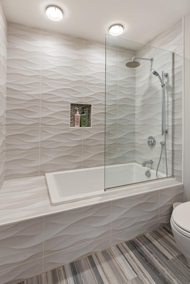 bathroom featuring tiled shower / bath combo and toilet