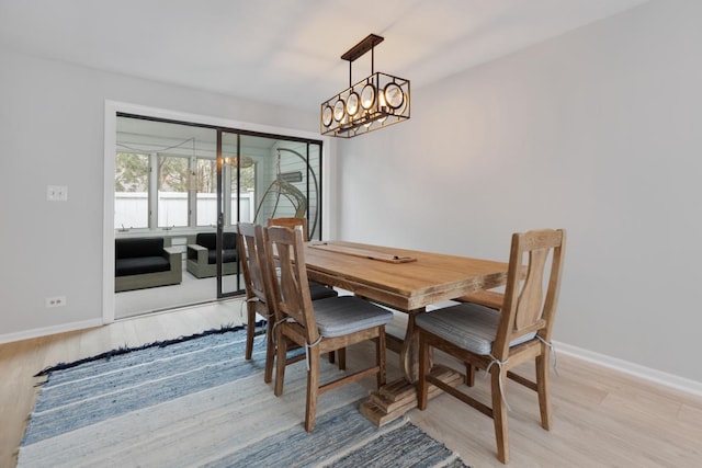 dining area with a chandelier, baseboards, and light wood-style floors