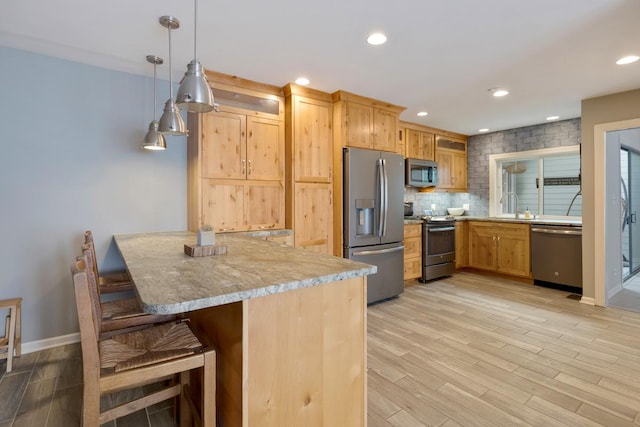 kitchen featuring light wood finished floors, stainless steel appliances, tasteful backsplash, light countertops, and a sink