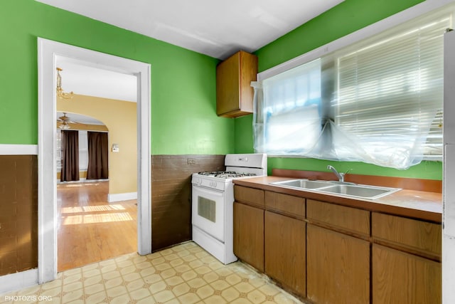 kitchen with sink, tile walls, ceiling fan, and white gas range oven