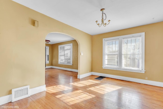 empty room with light hardwood / wood-style floors and a chandelier