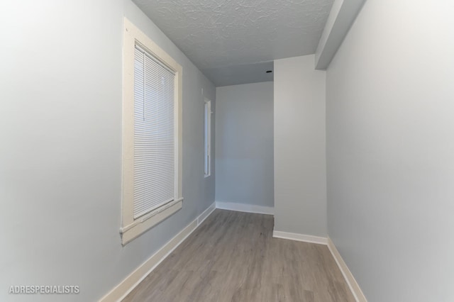 corridor featuring a textured ceiling and light hardwood / wood-style flooring