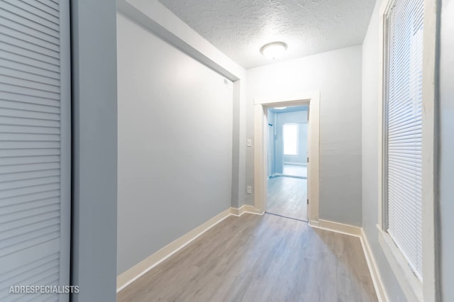 corridor featuring a textured ceiling and light hardwood / wood-style flooring