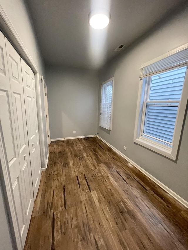 unfurnished bedroom with dark hardwood / wood-style flooring and a closet