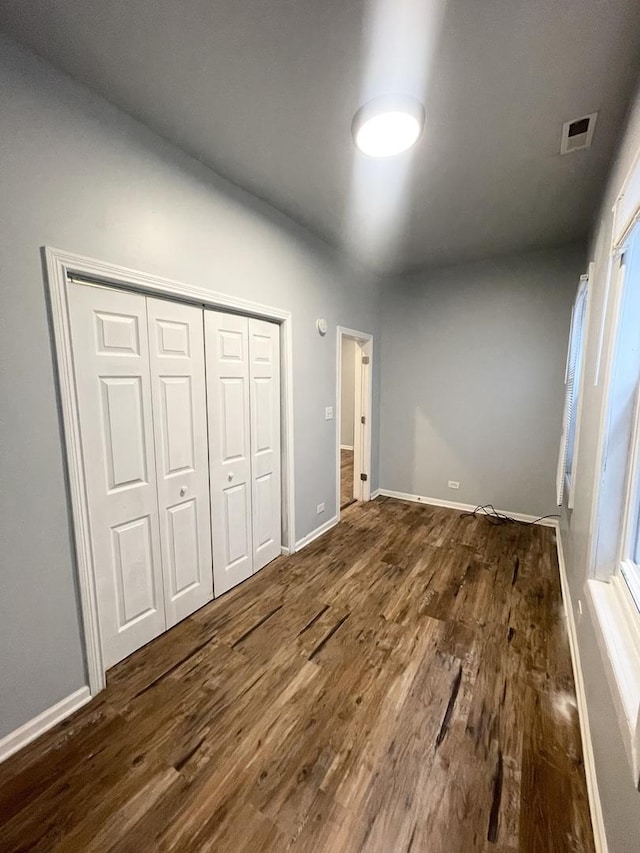 unfurnished bedroom featuring dark wood-type flooring and a closet