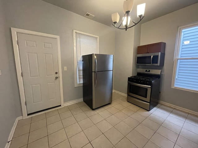 kitchen with a notable chandelier, light tile patterned floors, decorative light fixtures, and stainless steel appliances