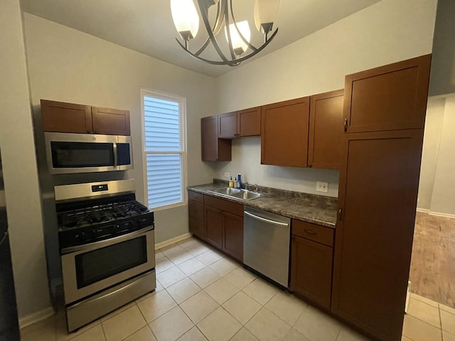 kitchen featuring pendant lighting, sink, light tile patterned floors, stainless steel appliances, and a chandelier