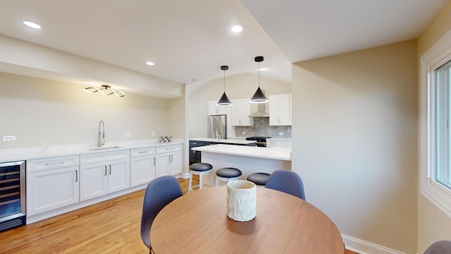 kitchen featuring stainless steel fridge, decorative light fixtures, sink, and white cabinets