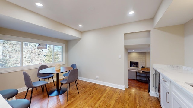 dining area featuring light hardwood / wood-style floors and a brick fireplace