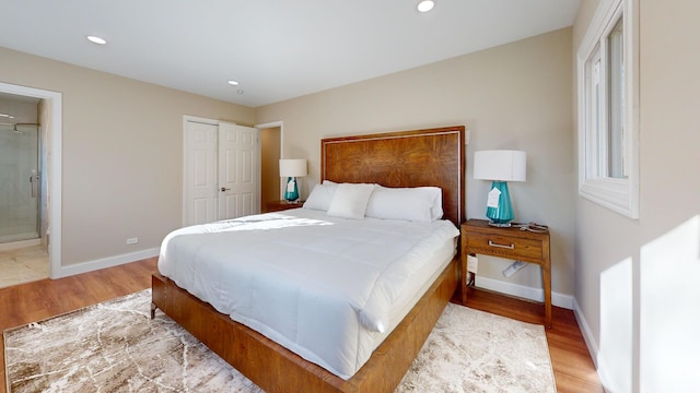 bedroom with connected bathroom, light wood-type flooring, and a closet