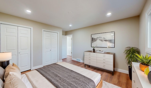 bedroom featuring light hardwood / wood-style floors and multiple closets