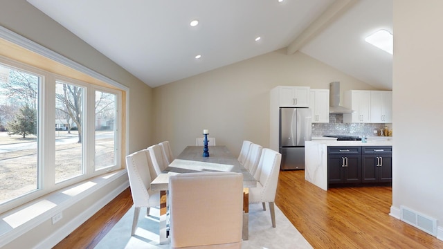 dining room with lofted ceiling with beams and light hardwood / wood-style flooring