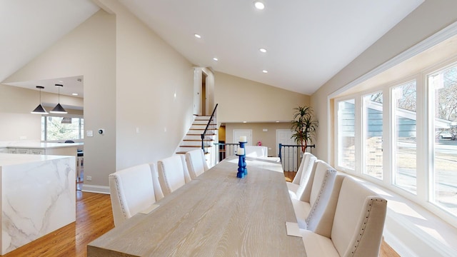 dining room featuring high vaulted ceiling and light wood-type flooring