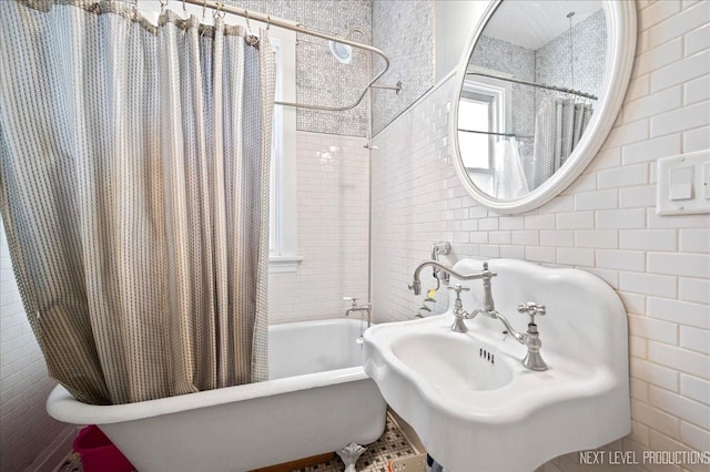 bathroom with sink, tile walls, and shower / bathtub combination with curtain