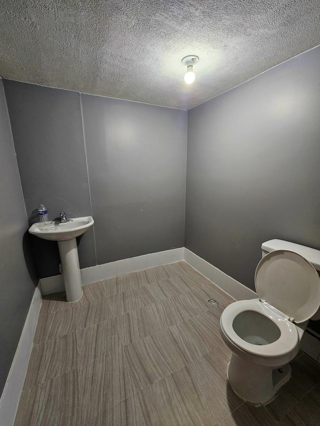 bathroom with sink, a textured ceiling, and toilet