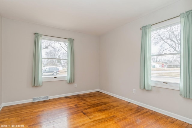 unfurnished room with hardwood / wood-style flooring and a healthy amount of sunlight